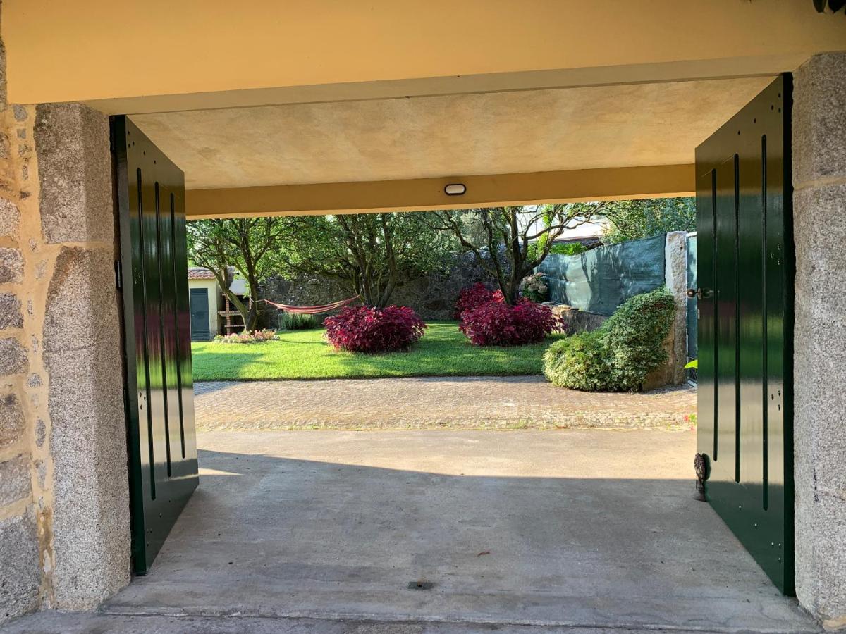 Portão de ferro aberto para jardim com árvores e caminho em terra