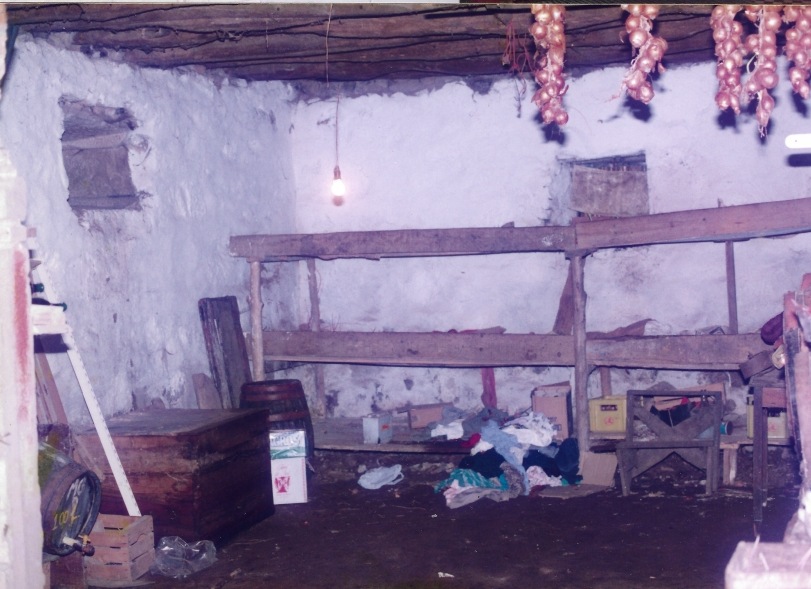 Fotografia antiga da loja em pedra da casa, com cebolas penduradas nas traves de madeira