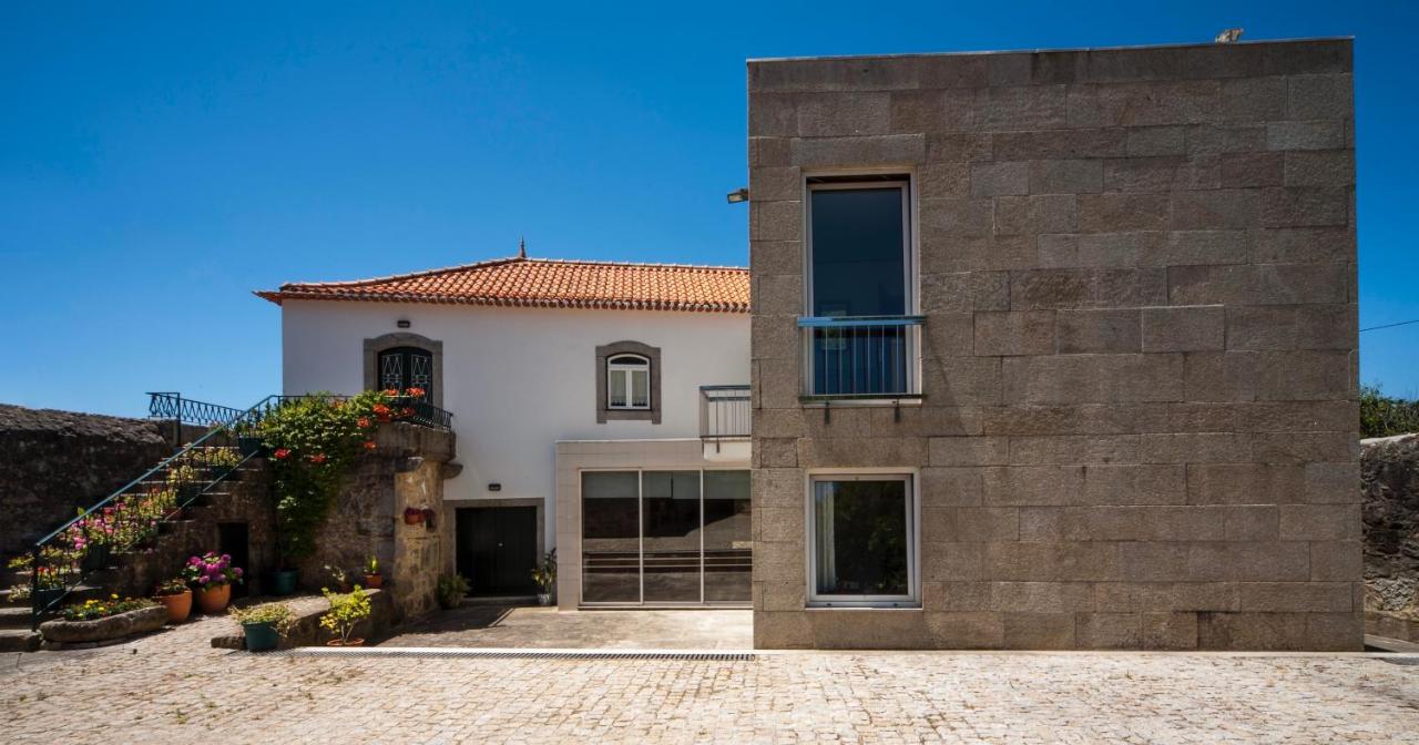 Vista lateral da casa com muro de pedra e portão