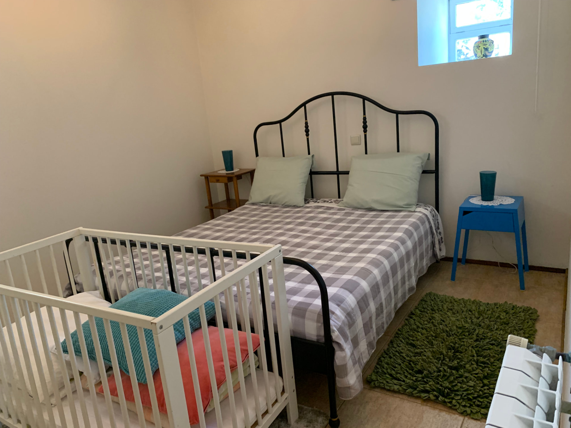 Quarto com cama de casal em ferro forjado e berço preparado para bebé
