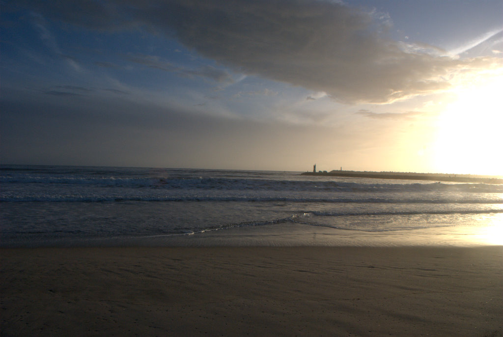 Praia do Cabedelo ao pôr do sol com farol ao longe
