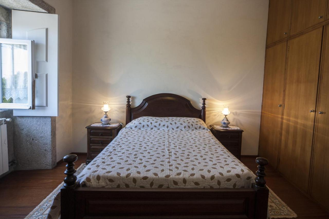 Quarto de casal com cabeceira em madeira maciça e roupa de cama clara