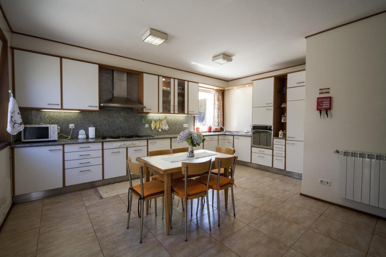 Cozinha atual totalmente equipada em branco, com mesa de refeições para toda a família
