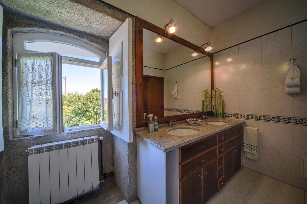 Casa de banho com dois lavatórios em granito e janela para o jardim