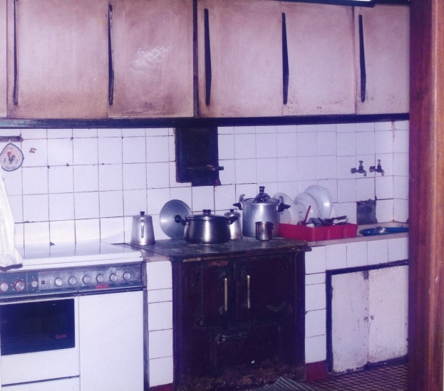 Fotografia antiga da cozinha da casa com fogão a lenha em ferro e azulejo branco