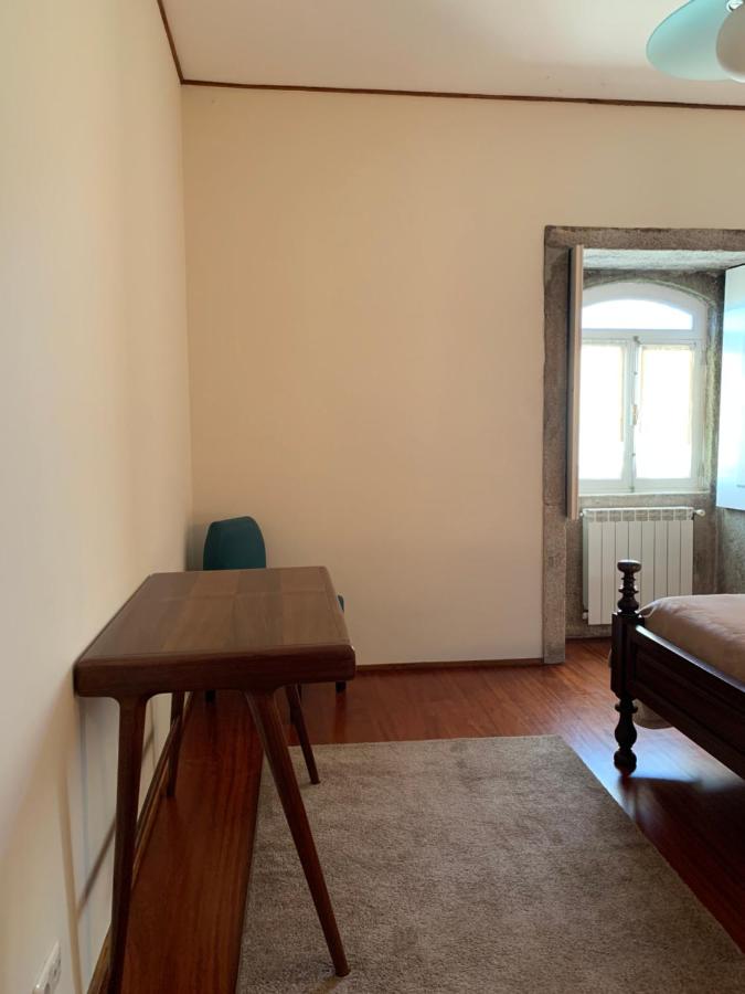 Quarto simples com secretária em madeira junto à janela